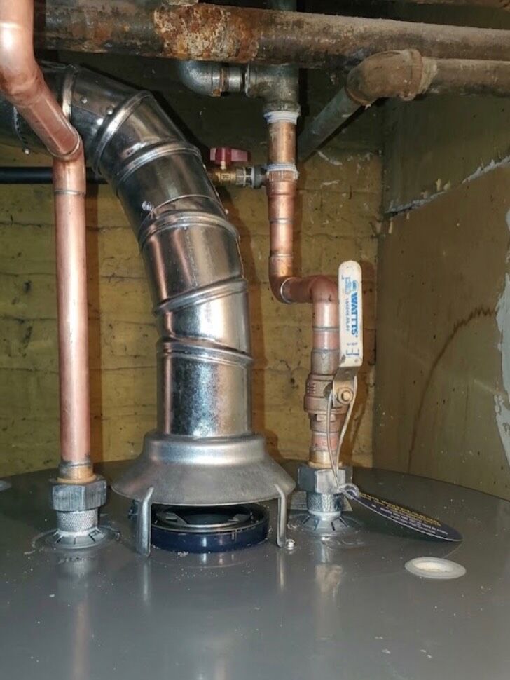 Copper piping and controls beside a basement gas water heater