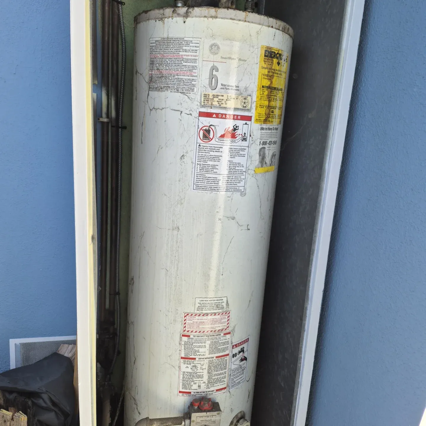 Corroded older water heater in a narrow utility space