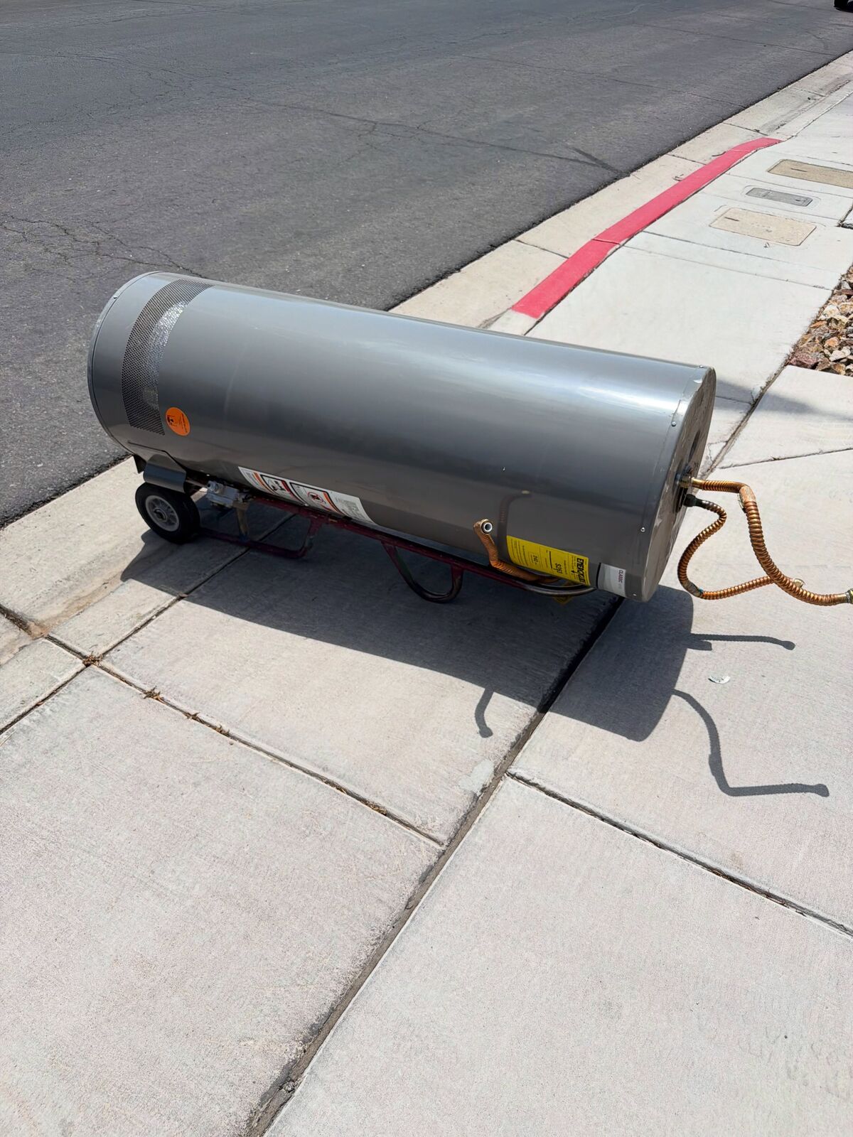 Older gas water heater before removal in a garage utility area